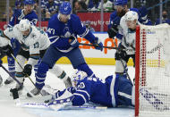 San Jose Sharks forward Nick Bonino (13) is boxed out by Toronto Maple Leafs forward Pierre Engvall (47) as Maple Leafs goaltender Michael Hutchinson (30) dives to cover the puck during the first period of an NHL hockey game Friday, Oct. 22, 2021, in Toronto. (Evan Buhler/The Canadian Press via AP)