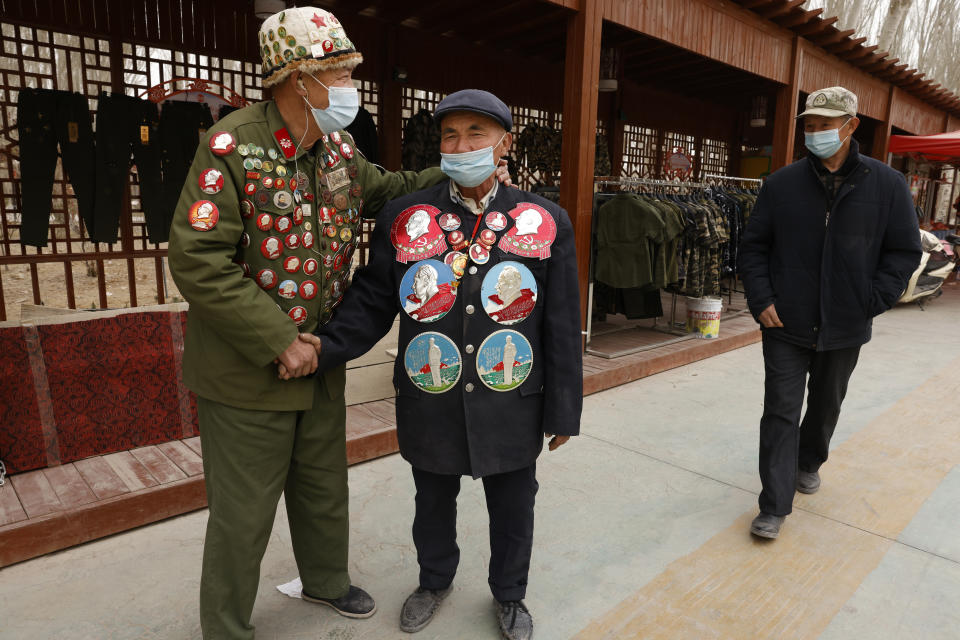 Ethnic minority veterans wearing commemorative buttons, some featuring Chairman Mao Zedong, greet each other at a flea market in Poksam county in northwestern China's Xinjiang Uyghur Autonomous Region on March 21, 2021. Four years after Beijing's brutal crackdown on largely Muslim minorities native to Xinjiang, Chinese authorities are dialing back the region's high-tech police state and stepping up tourism. But even as a sense of normality returns, fear remains, hidden but pervasive. (AP Photo/Ng Han Guan)