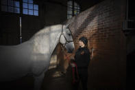 Fanny Lorre, 28, horsewoman at the Académie du Spectacle Equestre poses with her horse in the royal stables, in Versailles, Thursday, April 25, 2024. More than 340 years after the royal stables were built under the reign of France's Sun King, riders and horses continue to train and perform in front of the Versailles Palace. The site will soon keep on with the tradition by hosting the equestrian sports during the Paris Olympics. Commissioned by King Louis XIV, the stables have been built from 1679 to 1682 opposite to the palace's main entrance. (AP Photo/Aurelien Morissard)