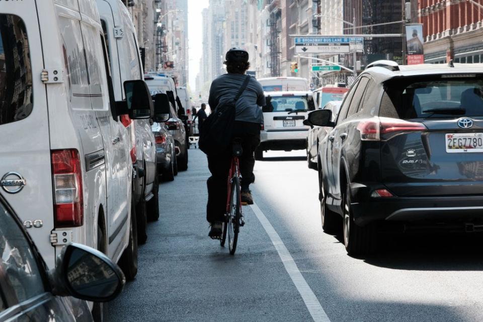 Cars sit in traffic in NYC as a biker passes on the shoulder.