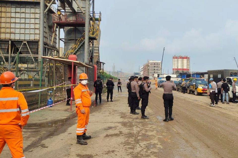 Police officers and workers stand near the site where a furnace explosion occurred at PT Indonesia Tsingshan Stainless Steel smelting plant in Morowali (AP)