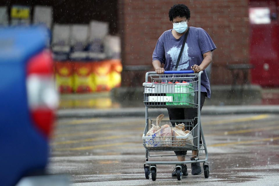 A shopper wears a mask as she pushes her grocery cart in the rain Thursday, June 25, 2020, in Houston. Texas Gov. Greg Abbott said Wednesday that the state is facing a "massive outbreak" in the coronavirus pandemic and that some new local restrictions may be needed to protect hospital space for new patients. (AP Photo/David J. Phillip)