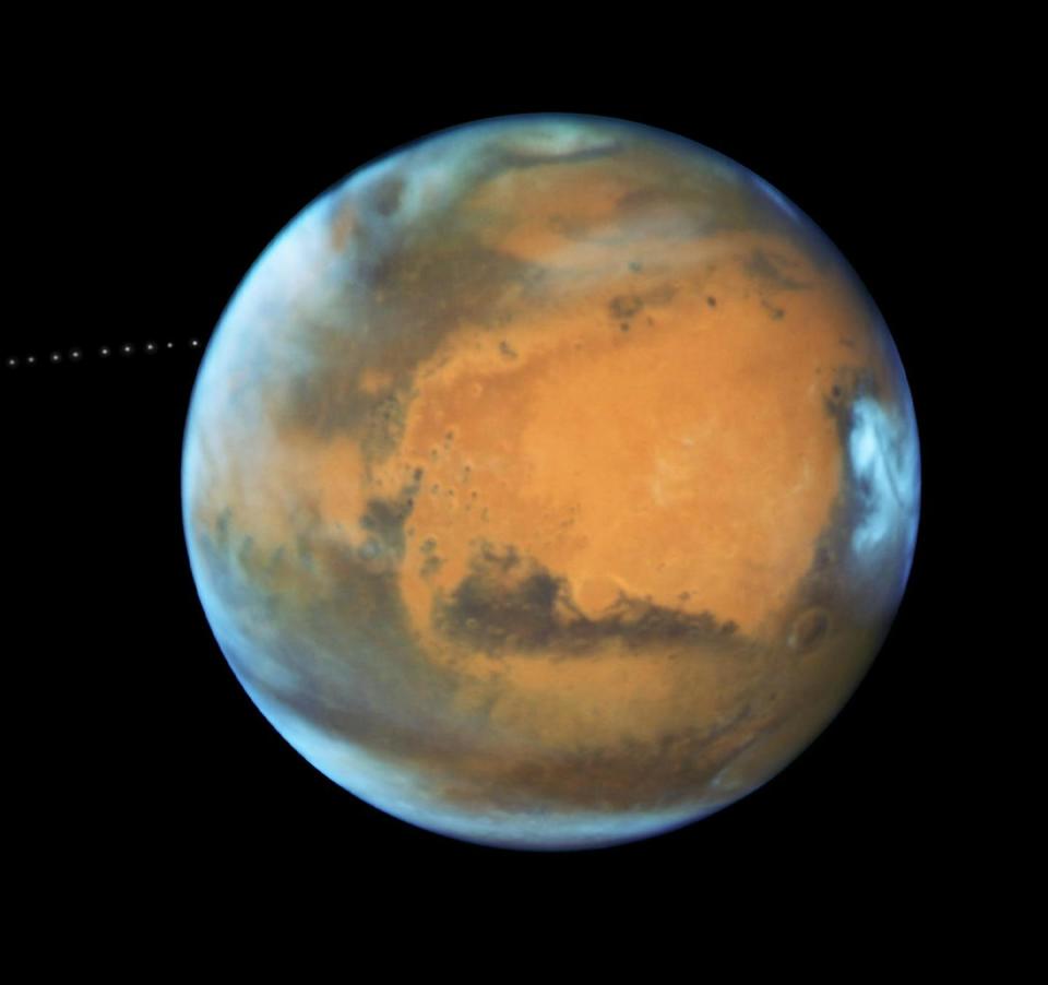 A photo of the planet Mars showing white caps and the reddish Martian surface.