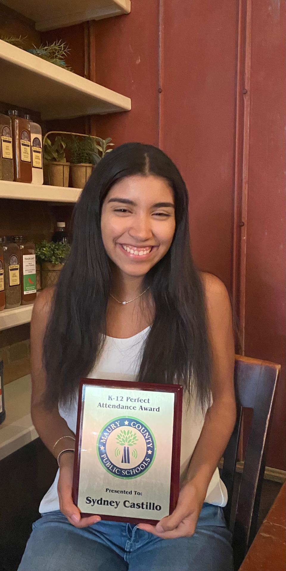 Sydney Castillo holds her Perfect Attendance Award for not missing a day of school from Kindergarten through twelfth grade while eating at Puckett's on Wednesday. Her father, Donald Castillo said Sydney never missed any Pre-Kindergarten either. Sydney's sister, Brianna, who starts at Central High School next year currently has perfect attendance as well.