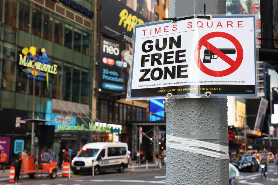 People walk past a "Gun Free Zone" sign posted on 40th Street and 7th Avenue on August 31, 2022 in New York City. Signs announcing a "gun-free zone" were posted at every entry and exit point of the Times Square area after a New York law limiting where firearms could be legally carried in public took effect last year. The state law was later overturned in court, but New York City passed a similar law designating Times Square as a "gun-free zone" in October 2022.