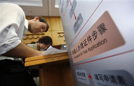 Foreigners fill up forms at Beijing's Exit & Entry Administration Service Center, September 3, 2013. Foreign executives in China are upset at a new rule that allows authorities to hold passports for up to 15 working days when processing and renewing residency permits, saying it could disrupt essential business travel within China and abroad. Picture taken September 3, 2013. REUTERS/Stringer