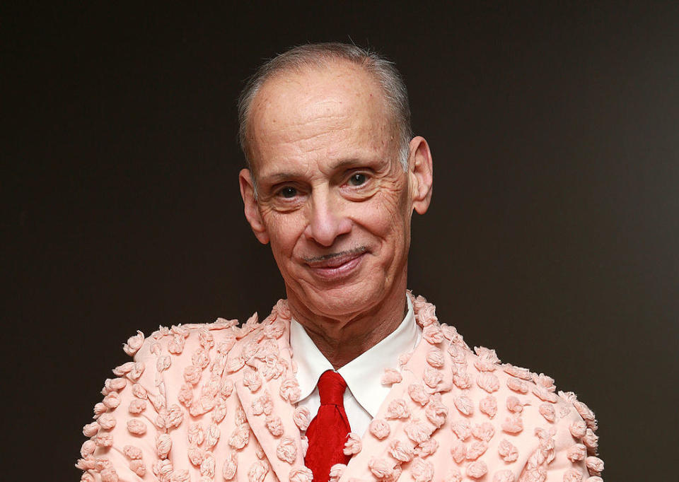 John Waters wearing a pink tufted suit at an event