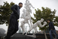 In this Friday, Oct. 11, 2019, photo, Chinese men walk by a sculpture depicting basketball players in Beijing. When Houston Rocket's general manager Daryl Morey tweeted last week in support of anti-government protests in Hong Kong, everything changed for NBA fans in China. A new chant flooded Chinese sports forums: "I can live without basketball, but I can't live without my motherland."(AP Photo/Ng Han Guan)