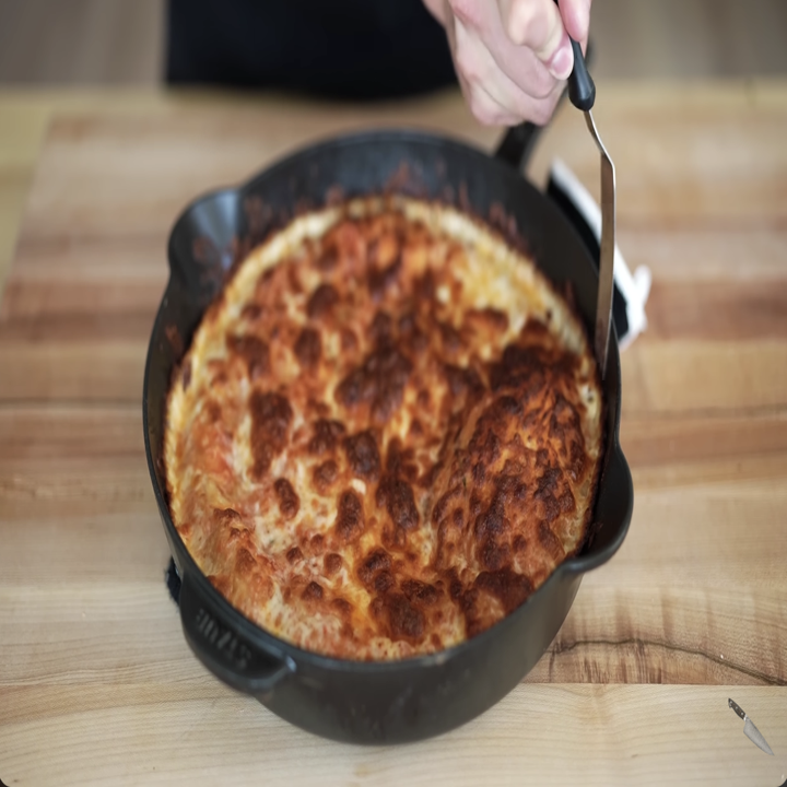 man making a pizza in a cast iron skillet