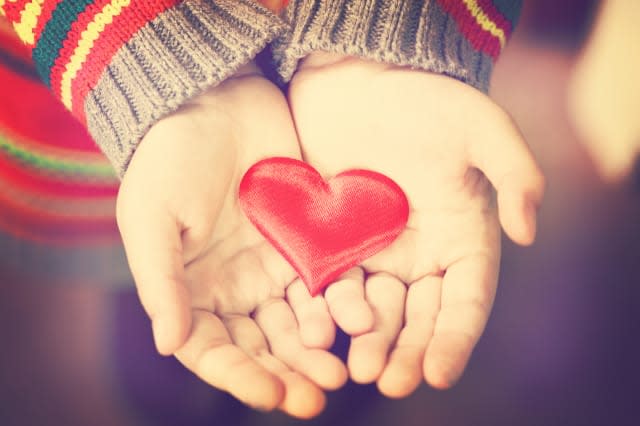 closeup of a girl's hands holding a red silky heart