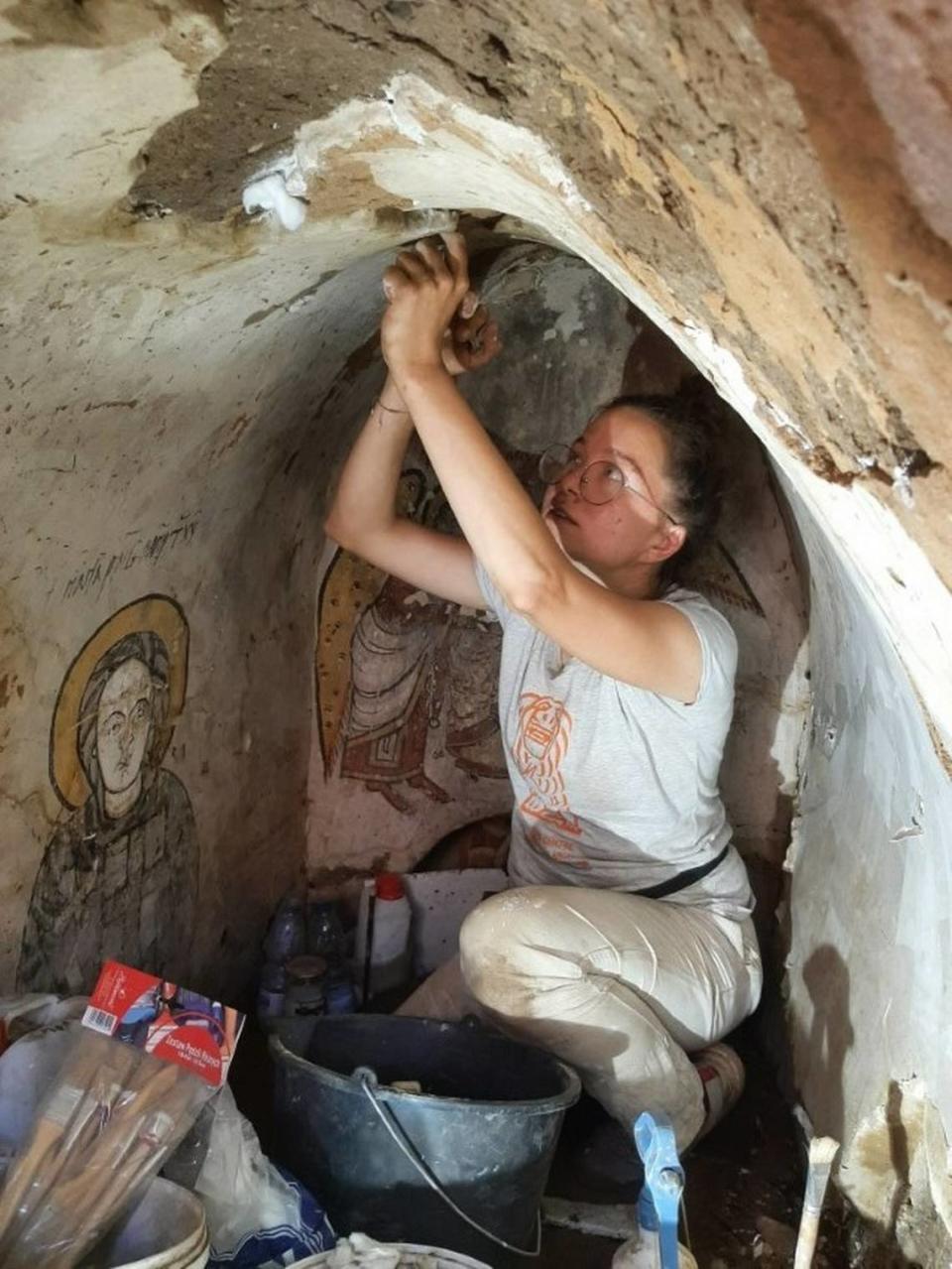 An archaeologists works to preserve the paintings in the underground chamber.