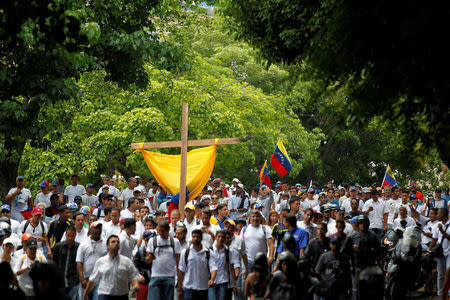 Demonstrators hold a cross as they take part in a rally to honour victims of violence during a protest against Venezuela's President Nicolas Maduro's government in Caracas, Venezuela, April 22, 2017. REUTERS/Christian Varon