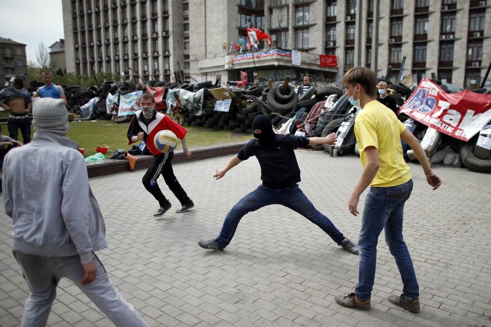 Pro-Russian protesters play soccer in front of a barricade outside a regional government building in Donetsk, eastern Ukraine April 19, 2014. A day after an international deal in Geneva to defuse the East-West crisis in Ukraine, pro-Russian separatists vowed not to end their occupation of public buildings and Washington threatened further sanctions on Moscow if the stalemate continued. REUTERS/Marko Djurica (UKRAINE - Tags: POLITICS CIVIL UNREST SOCIETY)