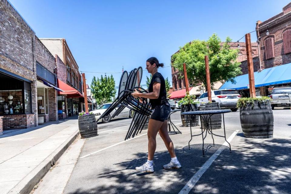 Veda Smith, an employee of Brick Coffee House Cafe, collects furniture out front Monday as businesses struggle with the closure of Highway 70 following the Hotel Marysville fire.