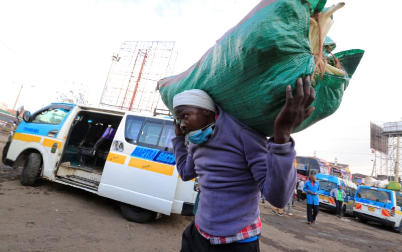 A passenger carries his load before boarding a disinfected public transport bus as residents leave for the villages amid concerns over the spread of coronavirus disease (COVID-19) in Nairobi