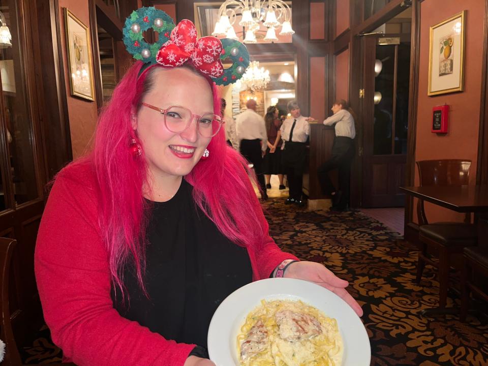 casey clark holding white plate of fettucini in tutto italia