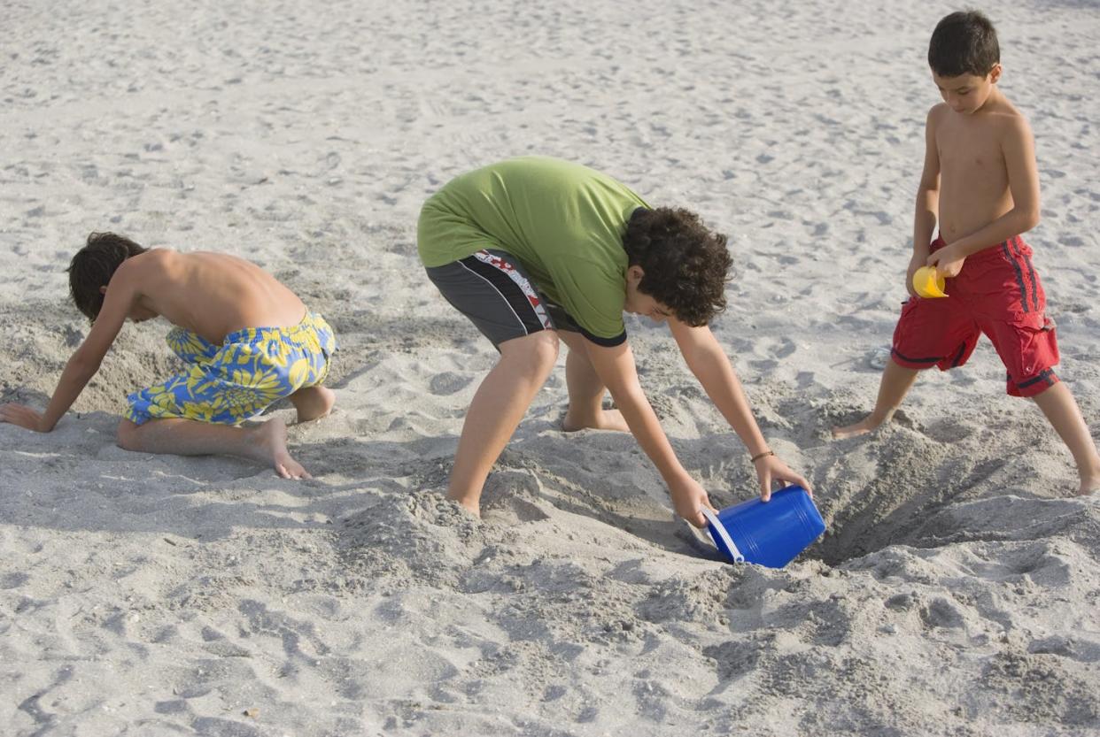 It's fun to take your kids to the beach, but keep an eye out for deep holes that could bury them. <a href="https://www.gettyimages.com/detail/photo/boys-digging-holes-at-beach-royalty-free-image/200445394-001?phrase=sand%2Bhole" rel="nofollow noopener" target="_blank" data-ylk="slk:Juan Silva/Photodisc via Getty Images;elm:context_link;itc:0;sec:content-canvas" class="link ">Juan Silva/Photodisc via Getty Images</a>