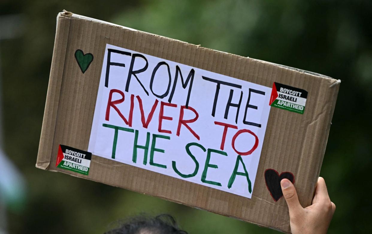 A Pro-Palestinian activist holds a placard reading 'From the River to the Sea' as they march through London on Saturday