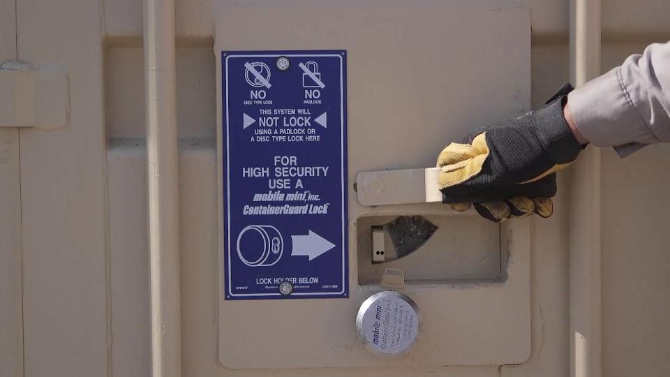 Hand holding handle of a storage unit, with instruction signage in blue.