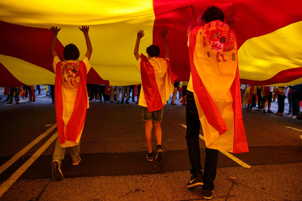 <p>Protesters draped in Spanish flags run under a giant Catalan flag during a pro-unity demonstration on Oct. 29, 2017 in Barcelona, Spain. (Photo: Jack Taylor/Getty Images) </p>