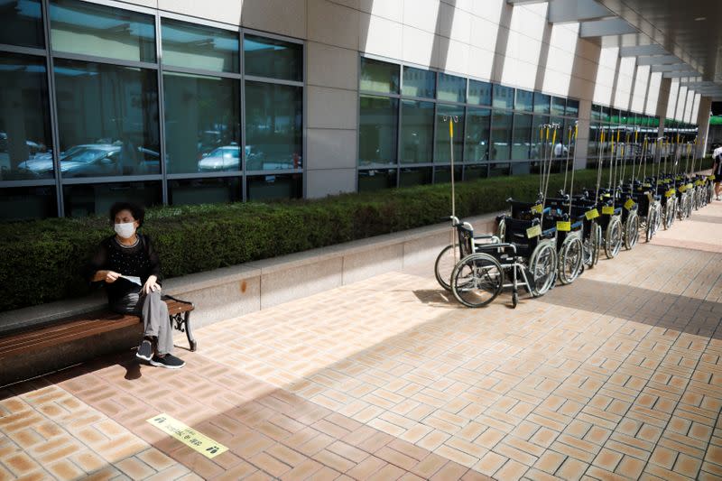 A woman wearing a mask to avoid the spread of the coronavirus disease (COVID-19) rests near wheelchairs for patients at a hospital in Seoul