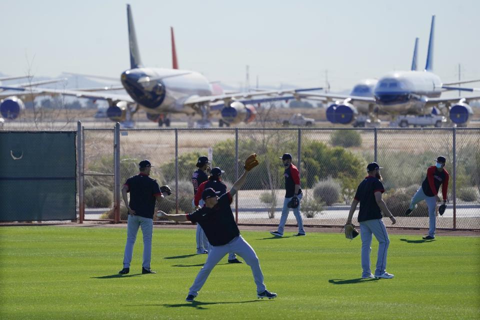With mothballed and retired passenger planes in the background at Phoenix Goodyear Airport, pitchers for the Cleveland Indians warm up during a spring training baseball practice Monday, Feb. 22, 2021, in Goodyear, Ariz. (AP Photo/Ross D. Franklin)