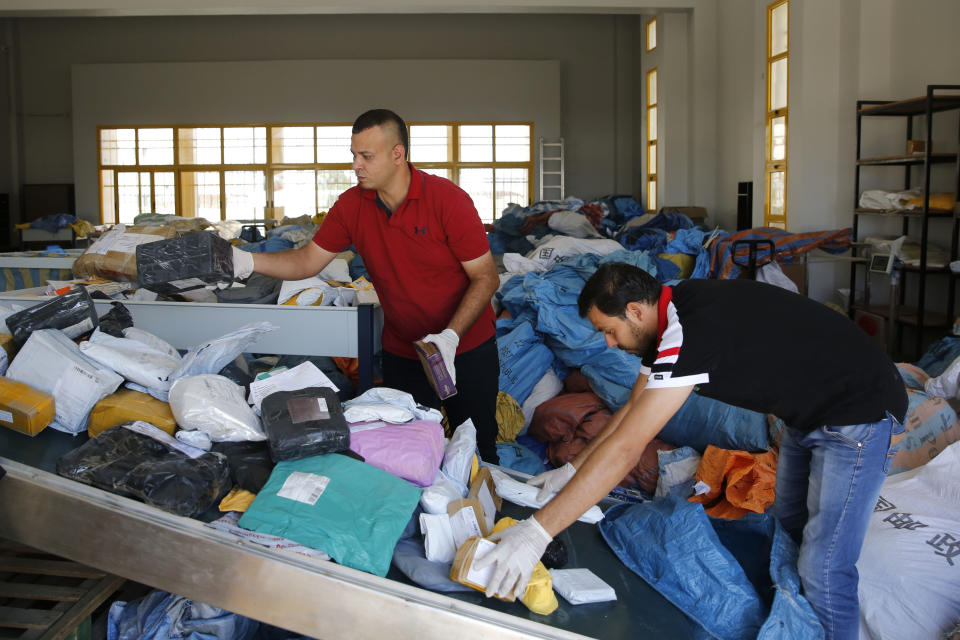 Palestinian postal workers sift through eight years' worth of undelivered mail held by Israel, at the post office in the West Bank city of Jericho, Sunday, Aug. 19, 2018. In recent days the postal staff has been sorting through tons of undelivered mail in a room packed with letters, boxes and even a wheelchair. Postal official Ramadan Ghazawi says Israel did not respect a 2008 agreement to send and receive mail directly through Jordan. Israeli officials say the one-time release of 10.5 tons of mail was a "gesture." (AP Photo/Nasser Shiyoukhi)