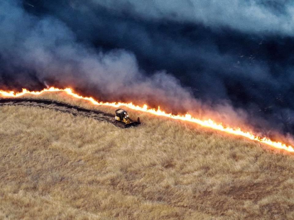 A firefighting bulldozer cuts a fire line Saturday, June 1, 2024, to stop progress of the Corral Fire, a 12,500-acre grass fire burning in San Joaquin County. Strong winds had pushed the blaze up to homes and a freeway south of Tracy.