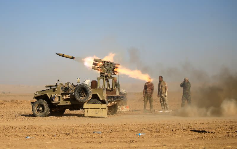 FILE PHOTO: Shi'ite fighters fire a rocket towards Islamic State militants during a battle with Islamic State militants at the airport of Tal Afar west of Mosul