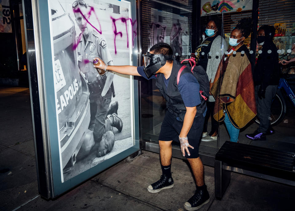 On May 31, a demonstrator in New York <a href="https://time.com/5845369/george-floyd-protests-malike-sidibe/" rel="nofollow noopener" target="_blank" data-ylk="slk:spray-paints;elm:context_link;itc:0;sec:content-canvas" class="link ">spray-paints</a> a poster of Derek Chauvin's knee on George Floyd's neck. "Out of nowhere, this guy pulled out a purple spray can and just started writing on it. These ladies were walking by and paused to look at it. They were looking at it, like, 'Is this to attack us or to stop us from being silent?'"<span class="copyright">Malike Sidibe for TIME</span>