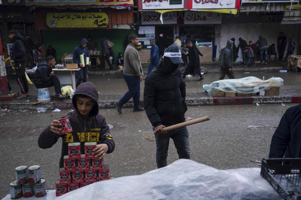 Masked men from The Popular Committee for Protection patrol the streets armed with batons and guns in Rafah, Gaza Strip, Thursday, March 7, 2024. The committee are a new youth-based group that monitors prices and law and order, across markets in war-ravaged Gaza. (AP Photo/Fatima Shbair)