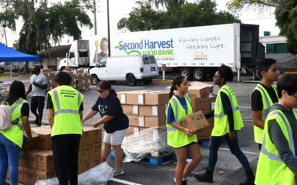 Volunteers move boxes of food for the needy at a food distribution event sponsored by the Second Harvest Food Bank of Central Florida and Orange County at St. John Vianney Church in Orlando, Florida. (Photo by Paul Hennessy/SOPA Images/LightRocket via Getty Images)