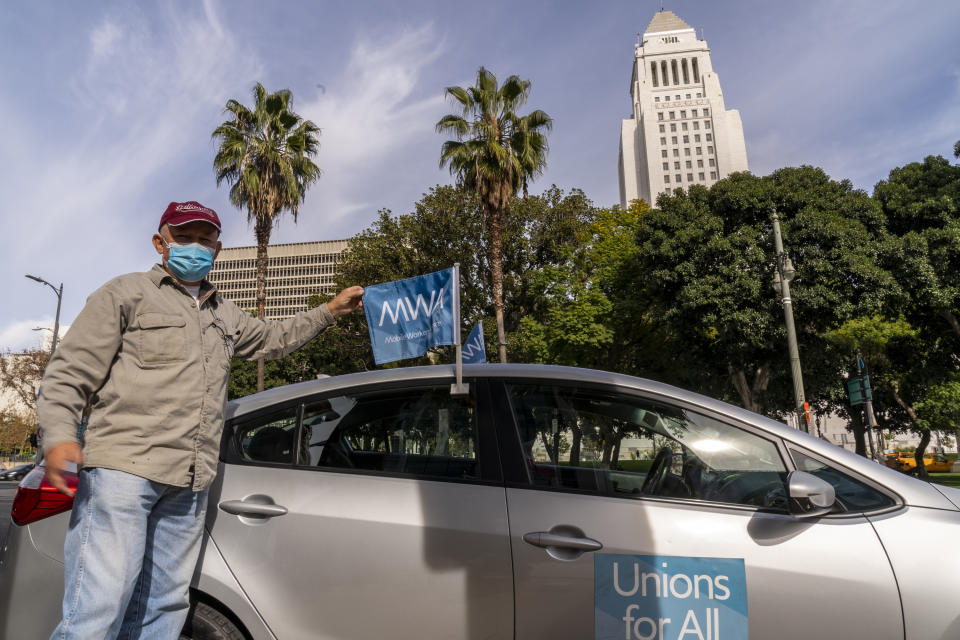 FILE - In this Jan. 12, 2021, file photo, Uber driver Jose Luis Guevara, a member of the Mobile Workers Alliance, pauses for a picture outside Los Angeles City Hall. A judge has struck down California’s ballot measure that exempted Uber and other companies from a state law requiring their drivers to be classified as employees eligible for benefits and job protections, Friday, Aug. 20. (AP Photo/Damian Dovarganes, File)