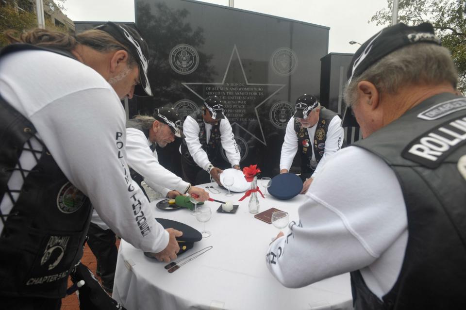 Members of Wilmington's Rolling Thunder veterans group places the hats of each branch of the military on each place set during "The Missing Man Table" ceremony at the Veteran's Memorial dedication on Water Street in 2009.  The ceremony symbolizes all the POW and MIAs that still lost from previous wars.