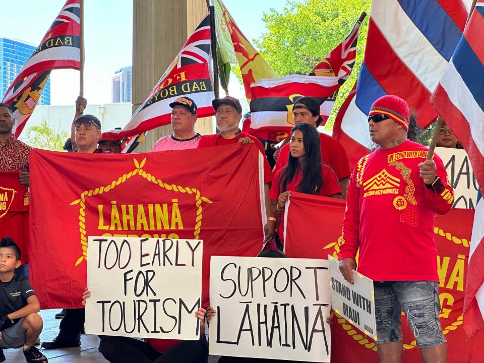 Lahaina residents and supporters hold signs and flags at the Hawaii State Capitol on Oct. 3 at a news conference asking Hawaii Gov. Josh Green to delay plans to reopen a portion of West Maui to tourism starting this weekend.