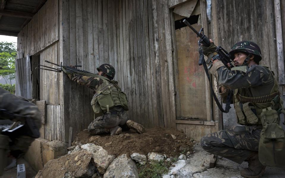 Soldiers firing at enemy positions while they try to clear the city of armed militants one street at a time - Credit: Jes Aznar/Getty Images