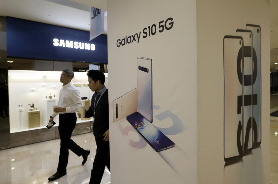 People pass by an advertisement of Samsung Electronics' Galaxy S10 5G smartphone at its shop in Seoul, South Korea, Friday, April 5, 2019. Samsung Electronics Co. said Friday its operating profit for the last quarter likely fell more than 60% from a year earlier amid falling memory chip prices and slowing demand for display panels. (AP Photo/Ahn Young-joon)