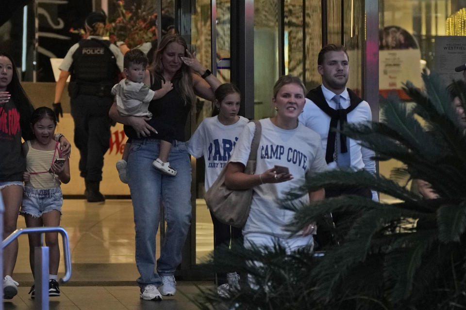 People are led out from the Westfield Shopping Centre where multiple people were stabbed in Sydney, Saturday, April 13, 2024. A man stabbed six people to death at the busy Sydney shopping center Saturday before he was fatally shot, police said. Multiple people, including a small child, were also injured in the attack. (AP Photo/Rick Rycroft)