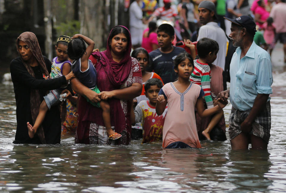 Sri Lankans wade through a road submerged in flood waters in Colombo, May 17, 2016. The Disaster Management Center said that 114 homes have been destroyed and more than 137,000 people evacuated as the heavy rains continued. (AP Photo/Eranga Jayawardena)