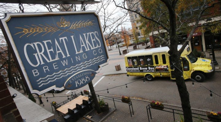 A Great Lakes Brewing Company sign hangs over the sidewalk with the Cleveland Brew Bus parked close by during a tour of holiday ale tour.  (John Kuntz / The Plain Dealer)
