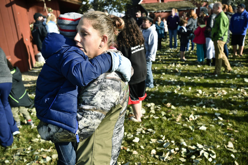 CORRECTS TO SAY WHAT AUTHORITIES THOUGHT WERE THE REMNANTS OF AN EXPLOSIVE DEVICE TURNED OUT TO BE A NONEXPLOSIVE DEVICE - Marnie Wedgwood hugs her son evacuated from the Rossiter Elementary School in Helena, Mont., Tuesday, Oct. 15, 2019, after authorities found what they thought were the remnants of an improvised explosive device on the school playground. Authorities evacuated the elementary school in Montana's capital city Tuesday after officials found the unknown materials, but they turned out to be a plastic bottle filled with nuts and bolts left in the schoolyard. (Thom Bridge/Independent Record via AP)