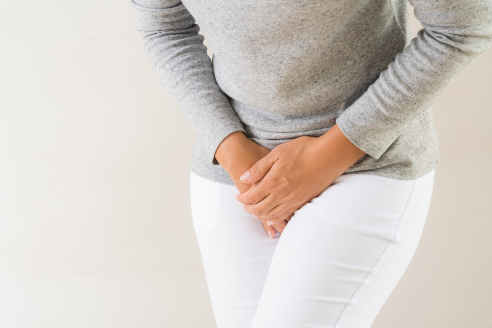 Young woman having painful stomachache with hands holding pressing her crotch lower abdomen. Medical or gynecological problems, healthcare concept