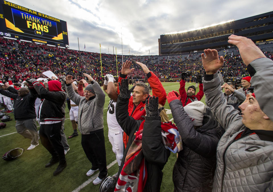 Ohio State head coach Urban Meyer (C) sings with his team and family members on the Michigan Stadium field on Saturday. (AP Photo/Tony Ding)