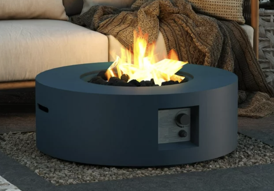 Dark blue circular lighted fire pit in front of white outdoor sofa