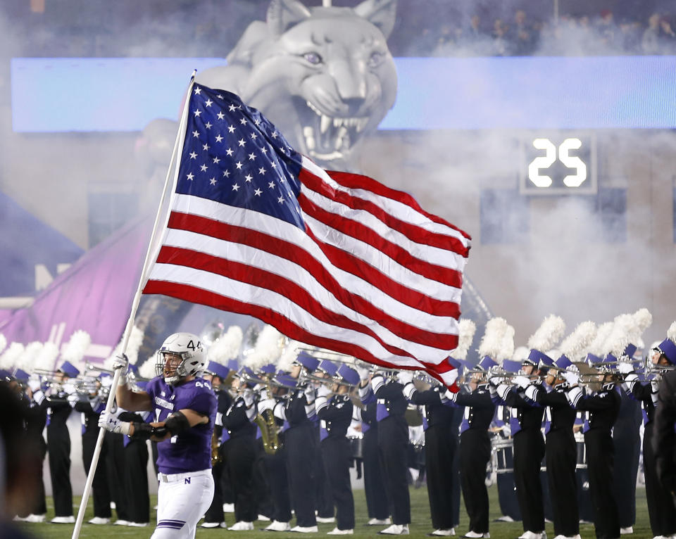 Northwestern's James Prather runs onto the field with a U.S. flag before the start of an NCAA college football game against Notre Dame Saturday, Nov. 3, 2018, in Evanston, Ill. (AP Photo/Jim Young)