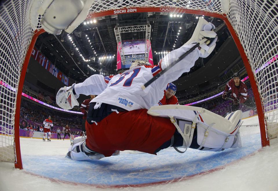 Latvia's Janis Sprukts (R) scores on goalie Ondrej Pavelec of the Czech Republic during the first period of their men's preliminary round ice hockey game at the Sochi 2014 Winter Olympic Games February 14, 2014. REUTERS/Mark Blinch/Pool (RUSSIA - Tags: SPORT ICE HOCKEY OLYMPICS)