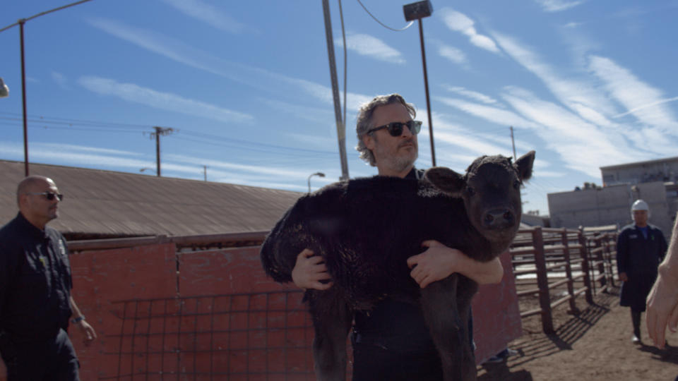 Joaquin Phoenix carries a baby calf away from a slaughterhouse. (Photo: Shaun Monson) 