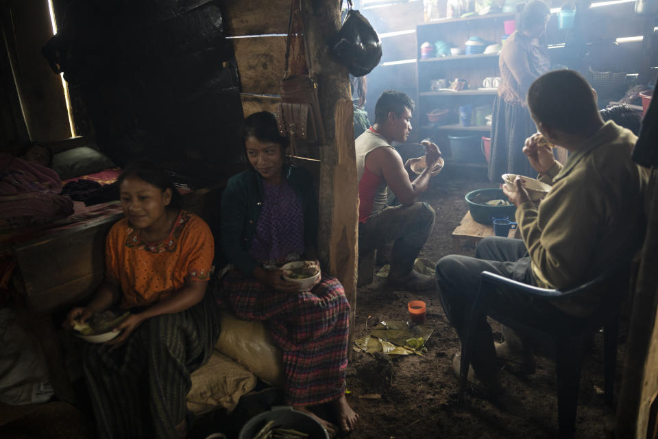 Members of the Hualim Lem family eat breakfast after working into the night killing a bull to sell the meat to neighbors, in the makeshift settlement Nuevo Queja, Guatemala, Tuesday July 13, 2021. The family are among the survivors of a mudslide triggered by Hurricane Eta that buried their Guatemalan town and now live in the temporary settlement founded close to their buried homes. (AP Photo/Rodrigo Abd)