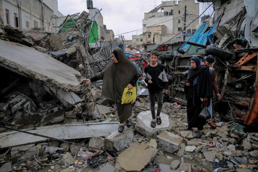 TOPSHOT - Palestinians walk amid debris of buildings hit in Israeli strikes, near Al-Zawiya market in Gaza City on November 27, 2023, on the fourth day of a truce in fighting between Israel and Hamas. The Israeli government said on November 27, it had put Hamas "on notice" that an "option for an extension" of the truce in the Gaza Strip was open. (Photo by Omar El-Qattaa / AFP) (Photo by OMAR EL-QATTAA/AFP via Getty Images)