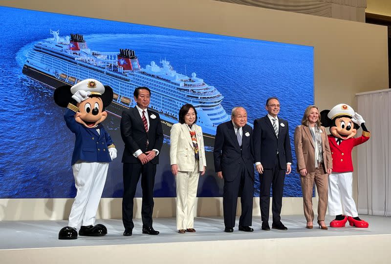 Disney and Oriental Land Co. executives pose with Disney characters at the unveiling of an expanded cruise line, in Urayasu